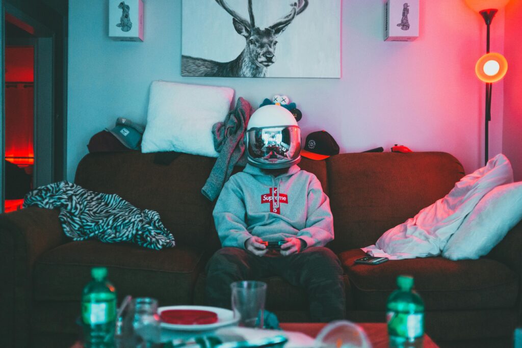 A person wearing a VR helmet, gaming on a couch in a cozy, neon-lit room.